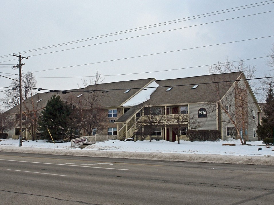 a house on the corner of a street in the snow