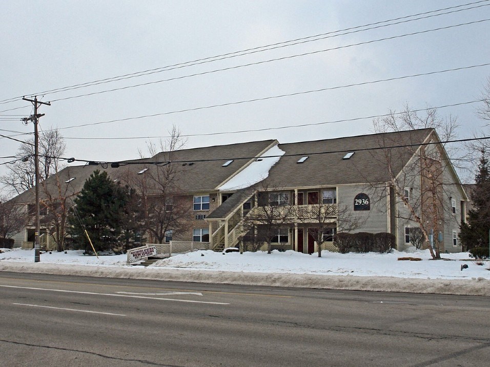 a house on the corner of a street in the snow