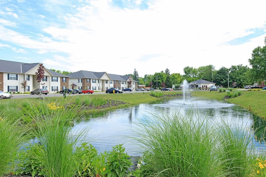 a pond with a fountain in front of a building