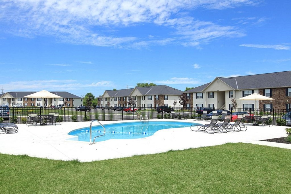 an outdoor pool with chairs and a building in the background