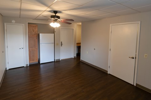 A room with a ceiling fan and wooden floors.