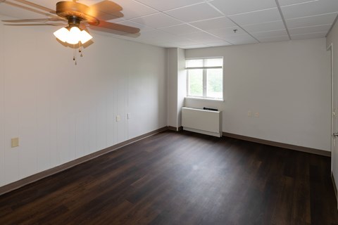 A room with a ceiling fan and a window.