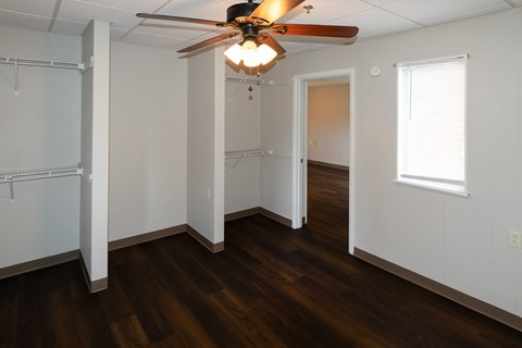A room with a ceiling fan and wooden floors.
