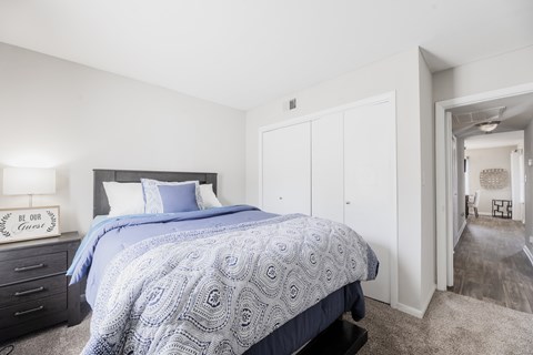 A bedroom with a bed, dresser, and a carpeted floor.
