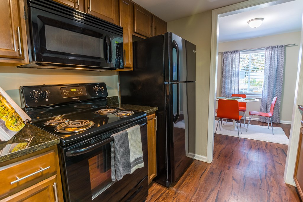 a kitchen with black appliances and wood flooring at Broadway at East Atlanta, Atlanta, GA