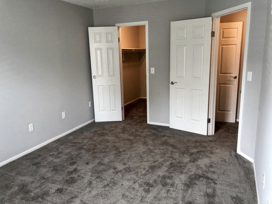 an empty living room with two doors and a carpeted floor