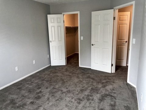 an empty living room with two doors and a carpeted floor