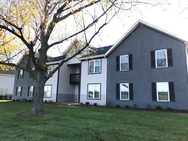 a gray house with a large tree in front of it