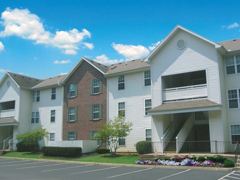 Apartment complex with a parking lot in front.