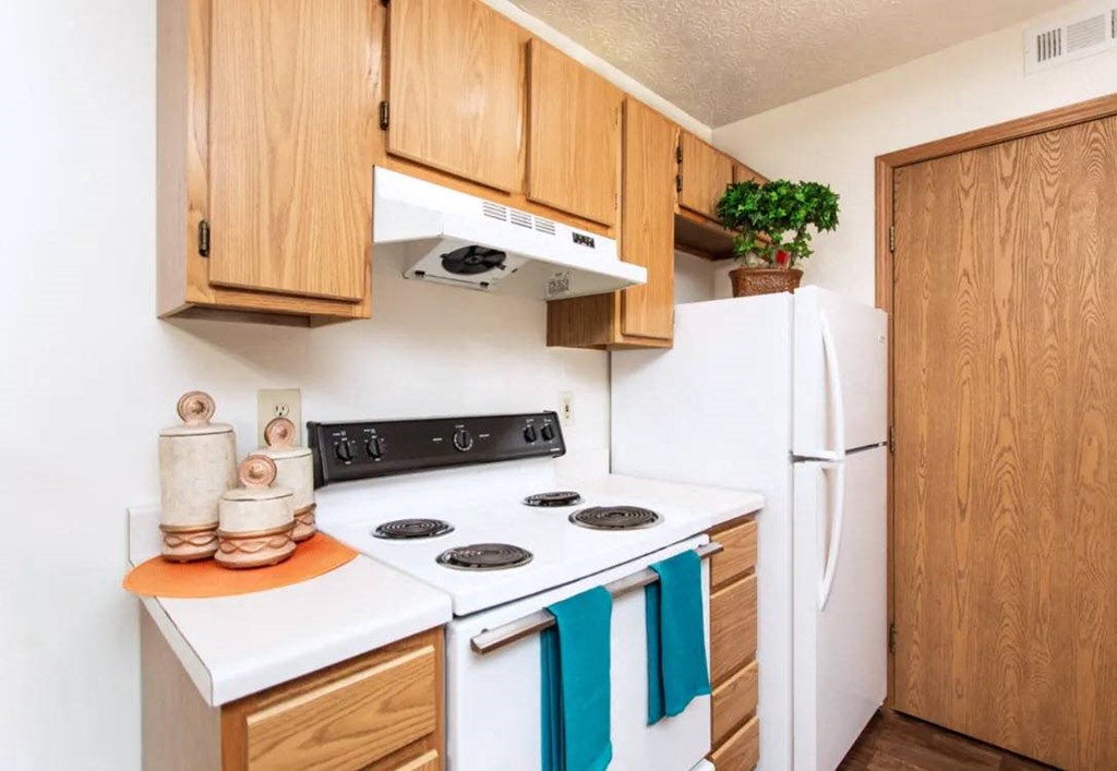 A kitchen with wooden cabinets and a white stove top oven.