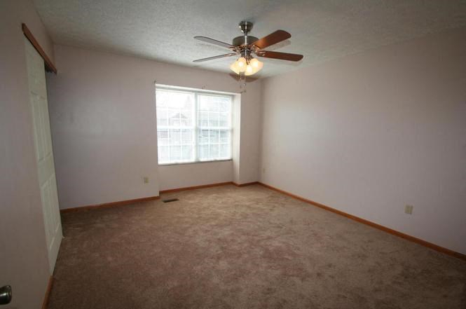 an empty room with a ceiling fan and a window