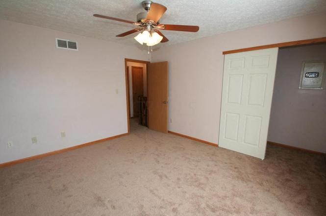 an empty living room with a ceiling fan