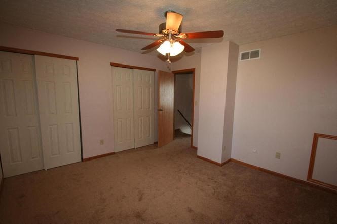 an empty living room with a ceiling fan
