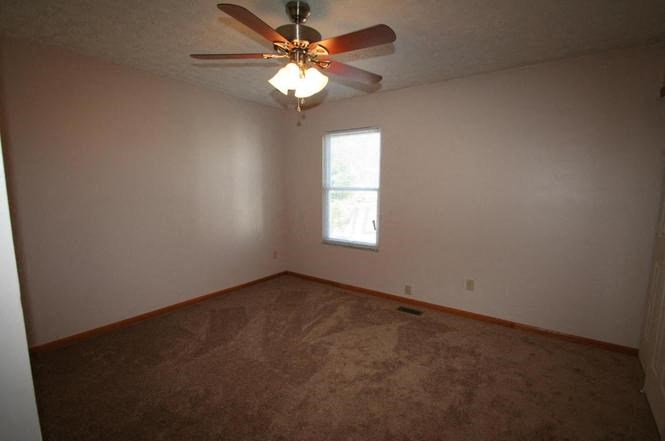 an empty room with a ceiling fan and a window