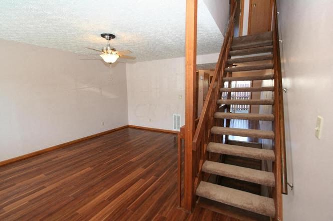 an empty room with a wooden staircase and a ceiling fan
