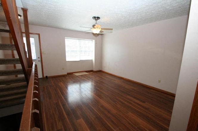 an empty living room with a ceiling fan and a stairs