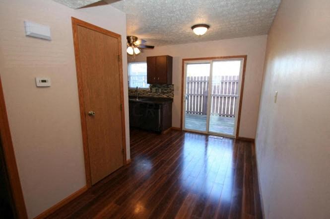 an empty living room with a door to a kitchen