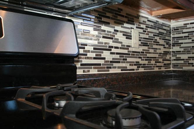 a stove top oven in a kitchen with a tile wall