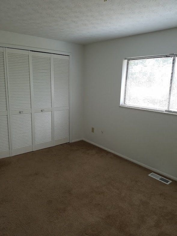 an empty room with a window and a closet