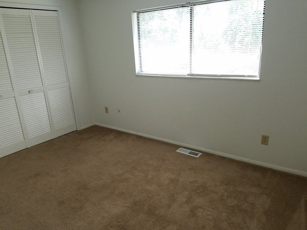 an empty room with a window and a closet