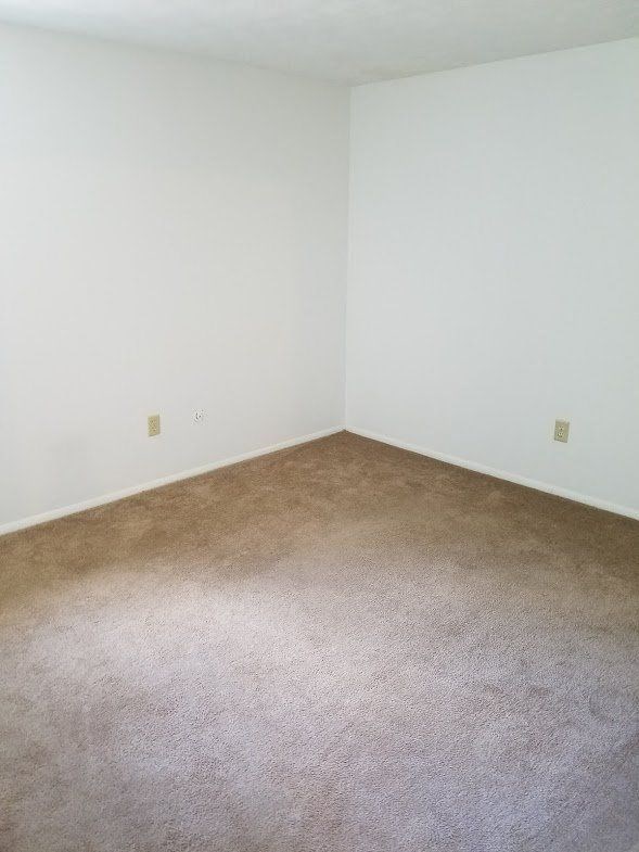an empty room with a carpeted floor and a white wall