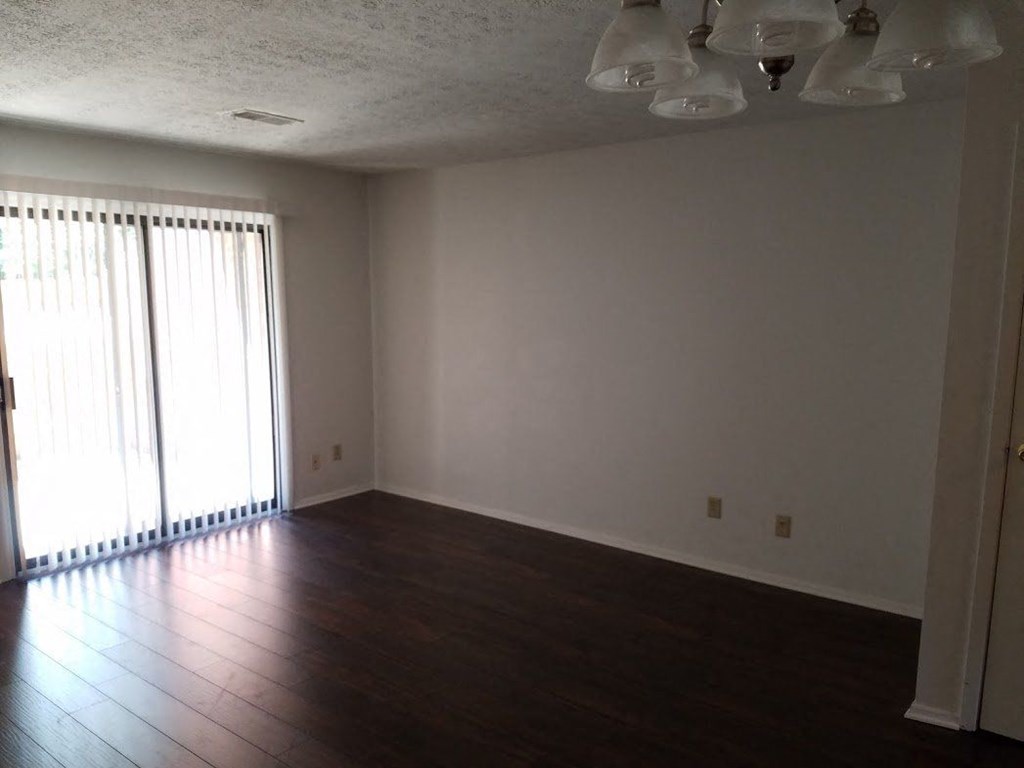 an empty living room with wood floors and a window