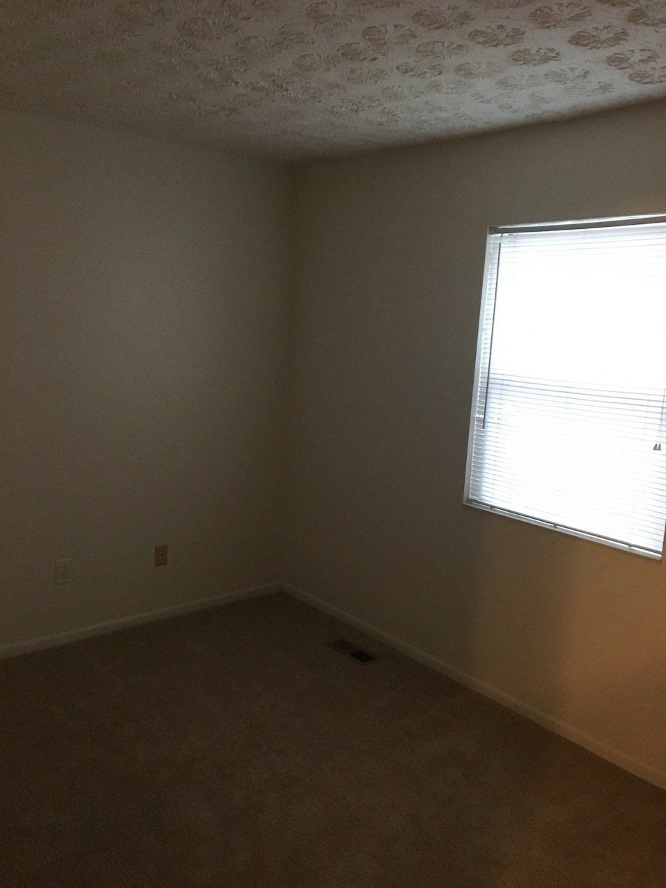 an empty room with a window and a carpet
