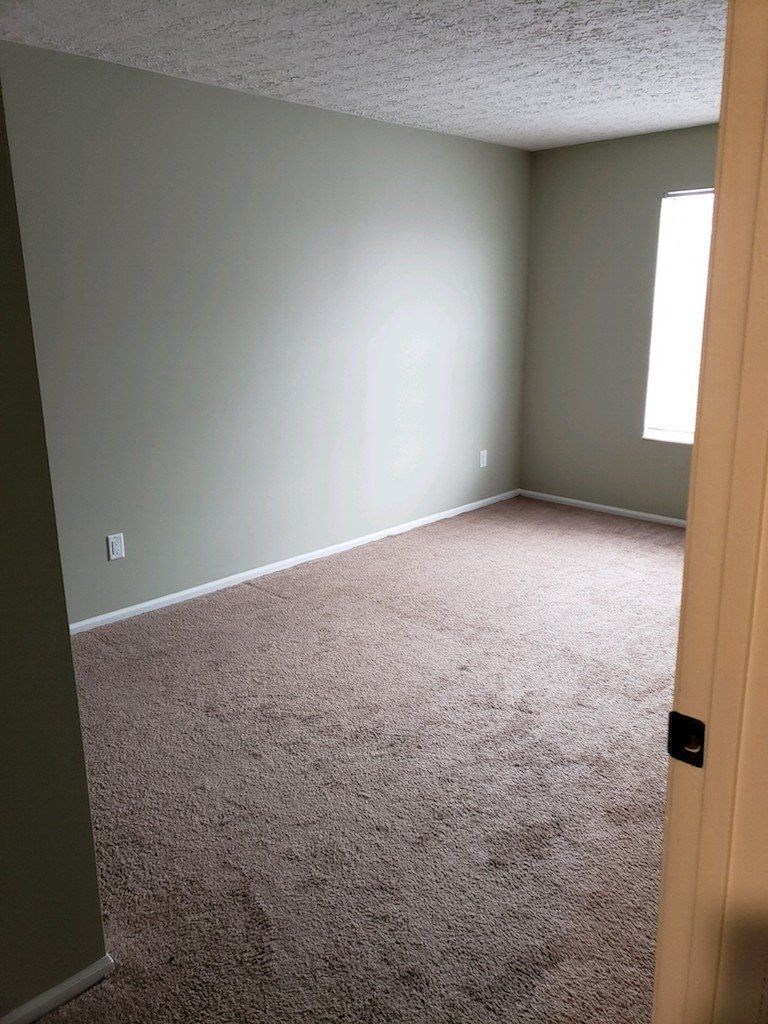 an empty room with a carpeted floor and a window