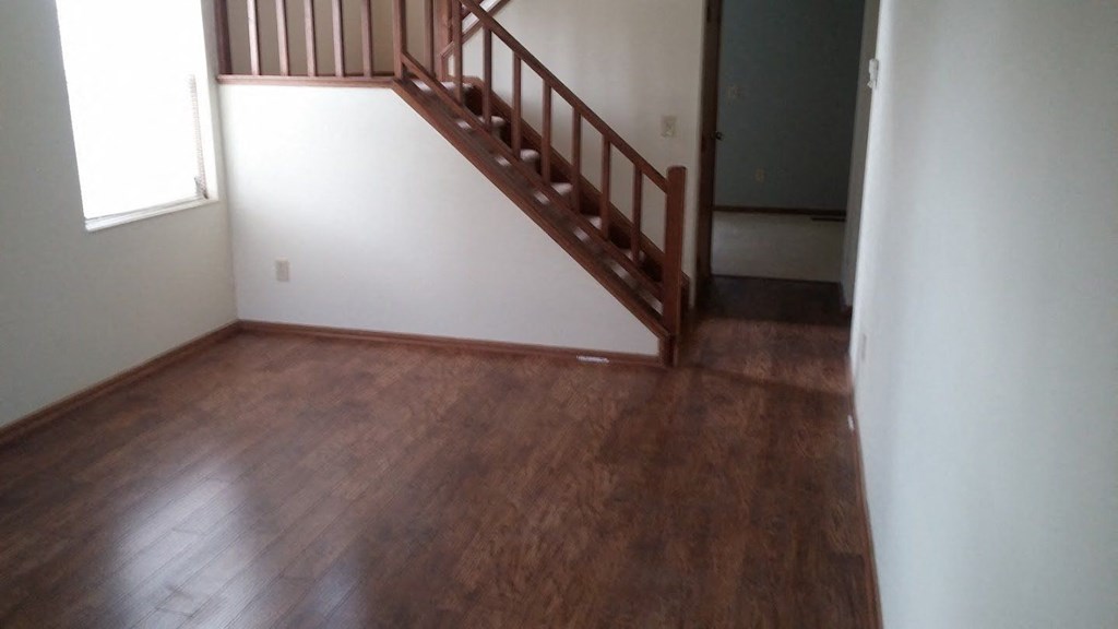 an empty living room with wood floors and a staircase
