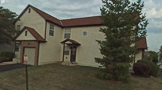 a white house with a red roof and a tree