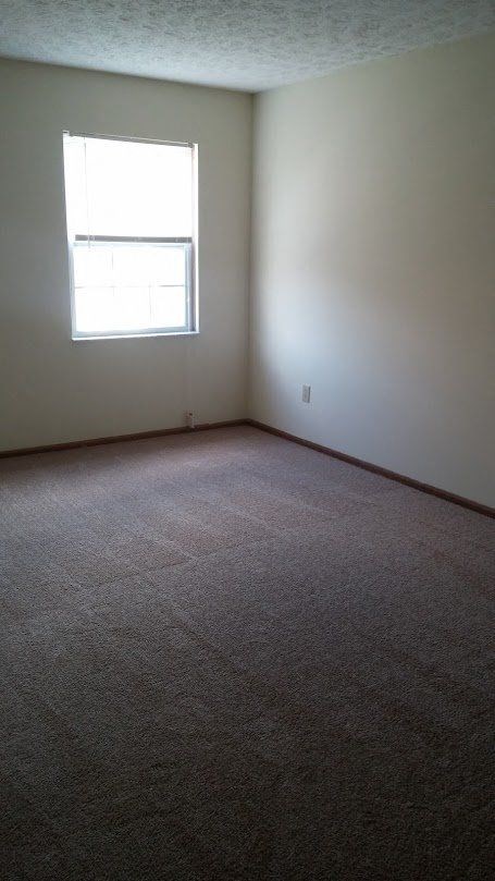 an empty room with a window and carpet