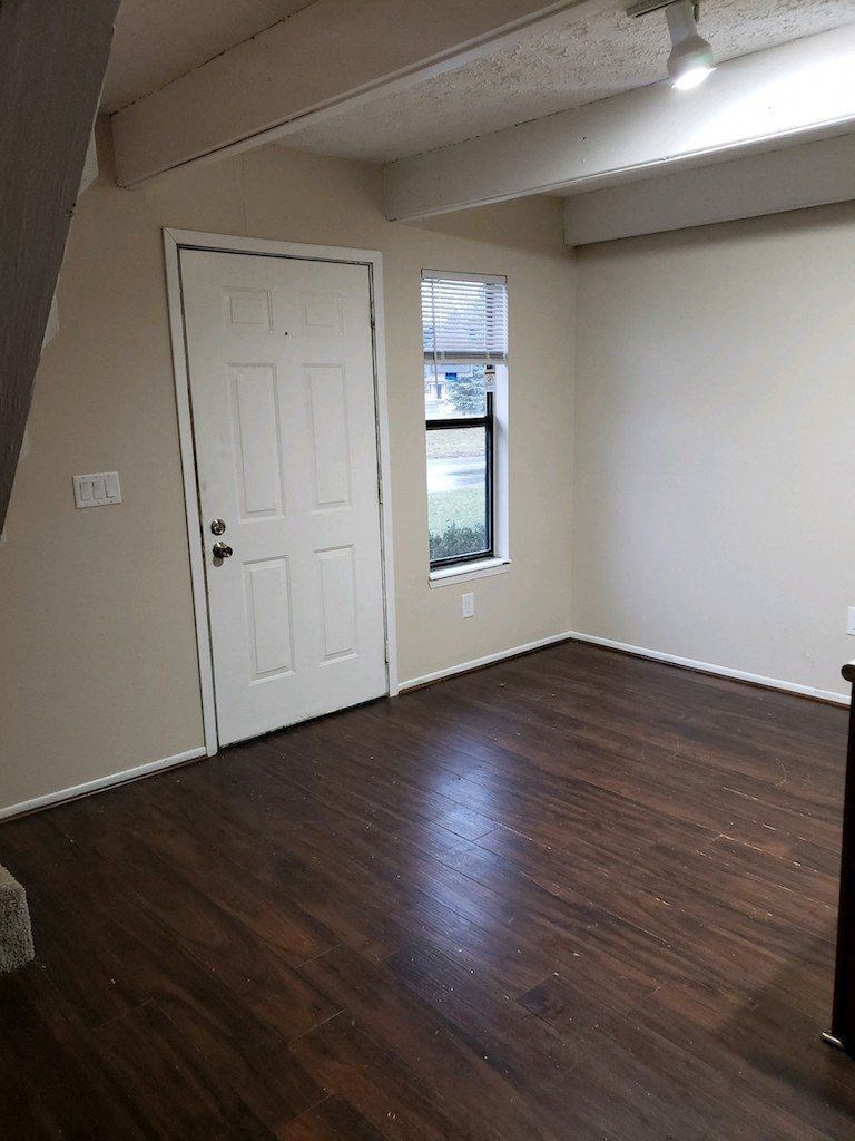 an empty living room with wooden floors and a white door