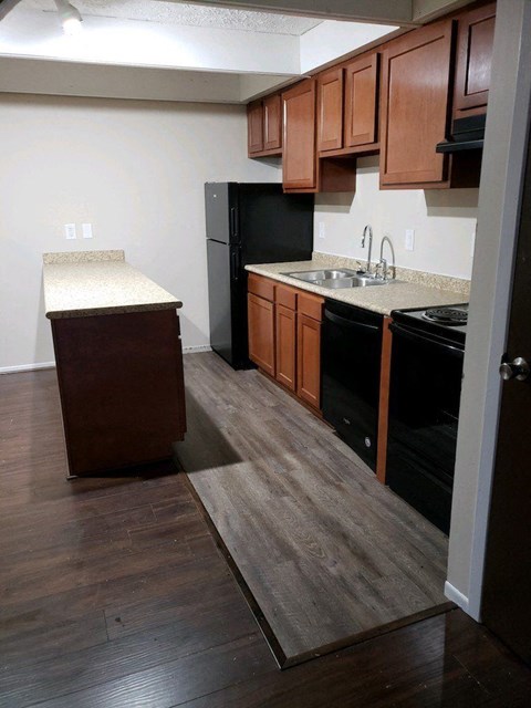 a kitchen with wooden floors and black appliances