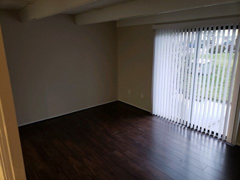 an empty living room with wood floors and a large window