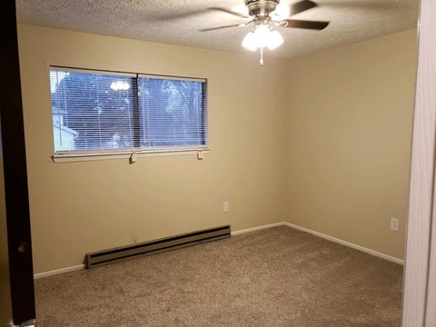 an empty room with a window and a ceiling fan