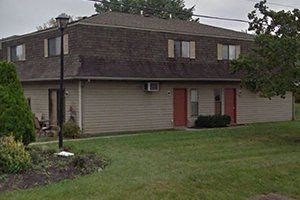 a white house with a red door and a yard