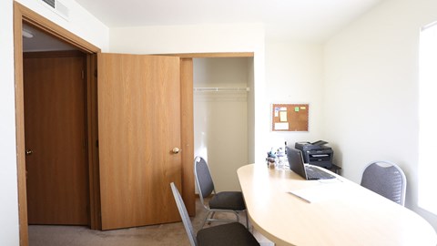 A conference room with a table, chairs, and a printer.