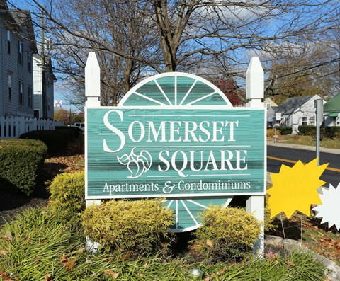A sign for Somerset Square Apartments & Condominiums is displayed in front of a building.