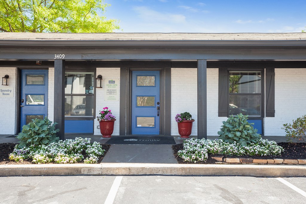 the front of a building with blue doors and plants