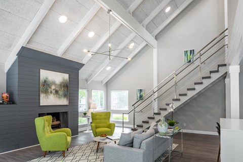 a living room with couches and chairs and a staircase