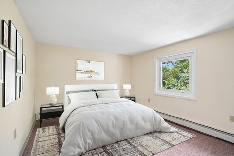 A bedroom with a large bed and a window showing greenery outside.