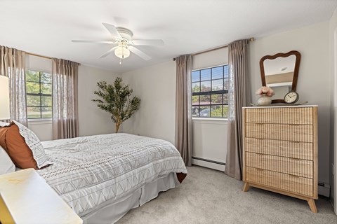 A bedroom with a bed, dresser, and window.
