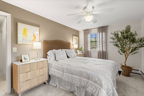A bedroom with a bed, nightstand, and a ceiling fan.