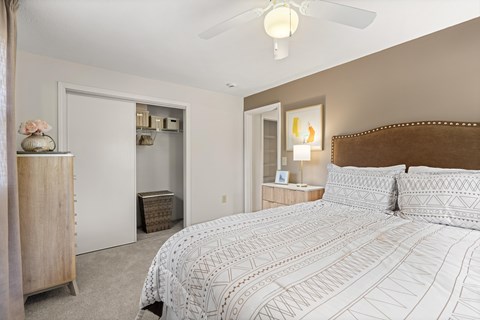 A bedroom with a large bed and a ceiling fan.