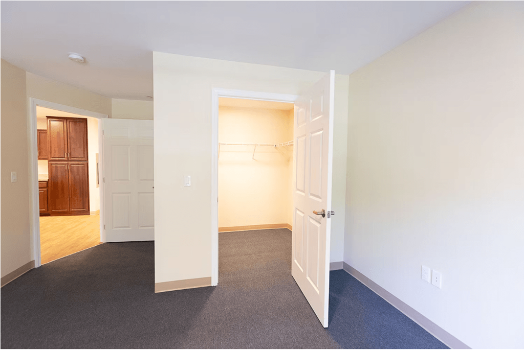A room with a carpeted floor and two open doors.