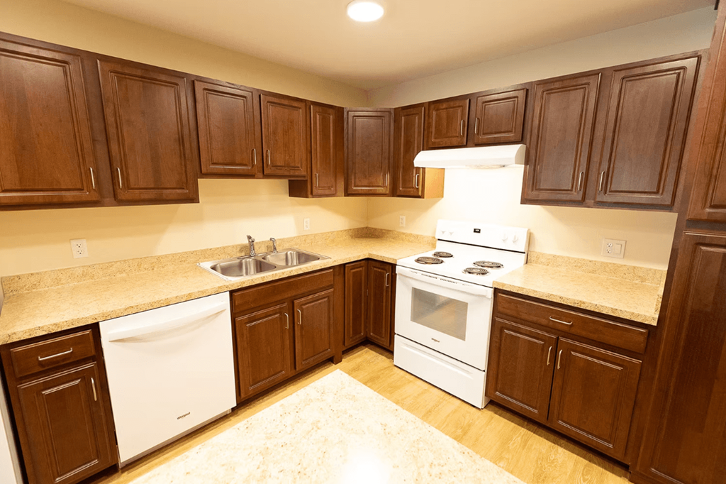 A kitchen with white appliances and brown cabinets.