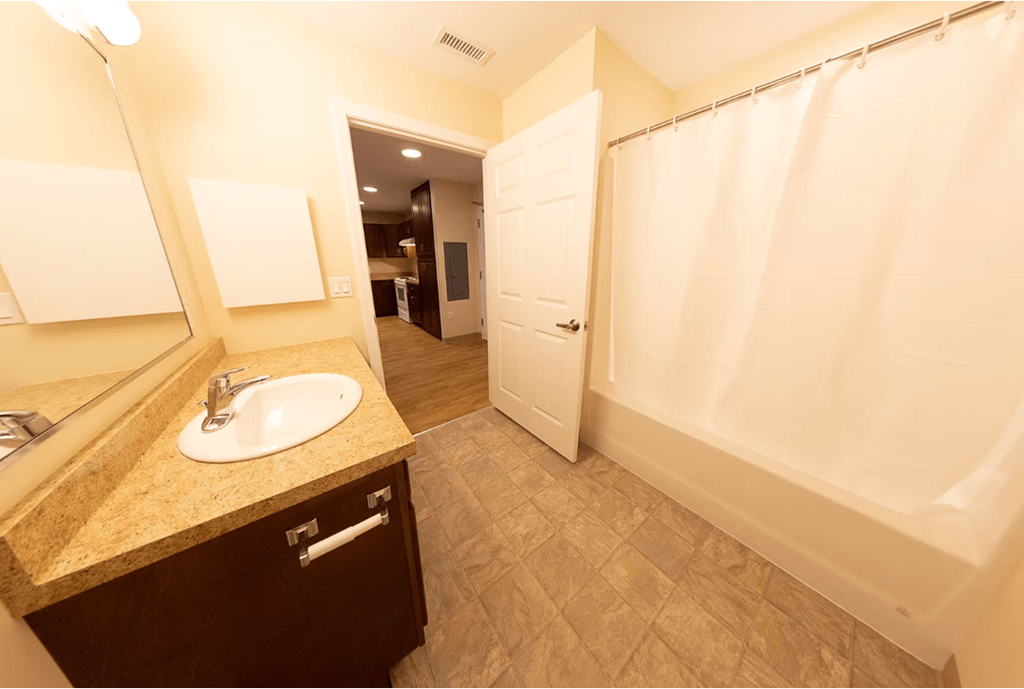 A bathroom with a sink, mirror, and shower.