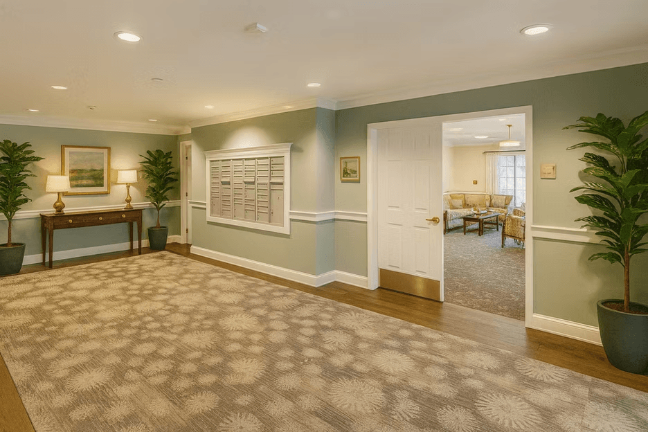 A hallway with a carpeted floor and a white door leading to a living room.