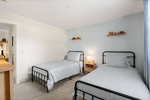 Two beds in a room with white walls and grey carpet.