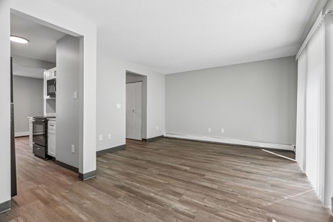 A spacious room with wooden flooring and white walls.